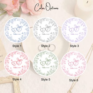 Puede incluir: Seis pegatinas redondas para recuerdos de boda con dise&ntilde;os de corazones florales en varios colores. Cada pegatina presenta las iniciales "F" y "J" y la fecha "01 de octubre de 2025". Las pegatinas est&aacute;n etiquetadas como "Estilo 1" a "Estilo 6".