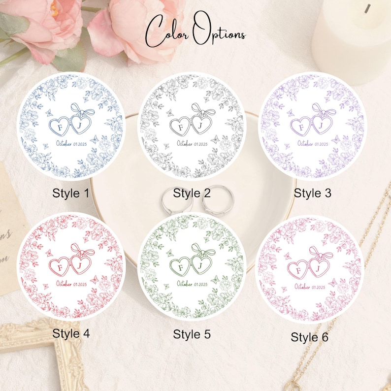 Puede incluir: Seis pegatinas redondas para recuerdos de boda con dise&ntilde;os de corazones florales en varios colores. Cada pegatina presenta las iniciales "F" y "J" y la fecha "01 de octubre de 2025". Las pegatinas est&aacute;n etiquetadas como "Estilo 1" a "Estilo 6".