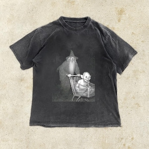 May include: Dark gray t-shirt featuring a black and white graphic of a wizard pushing a shopping cart with a creature inside. The t-shirt has a crew neck and short sleeves. The graphic is centered on the front of the shirt.