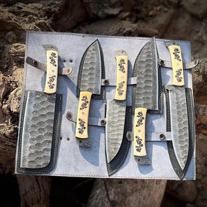 Handmade 5 piece chef knife set featuring natural white handles crafted from natural material with high carbon steel blades arranged inside a premium hand stitched leather roll kit. The image shows the complete kitchen knife collection designed for professional chefs and home cooks who love quality tools. This artisan knife set is perfect for anniversary gifts, wedding gifts, housewarming presents and culinary collectors looking for beautiful handmade kitchen knives with safe