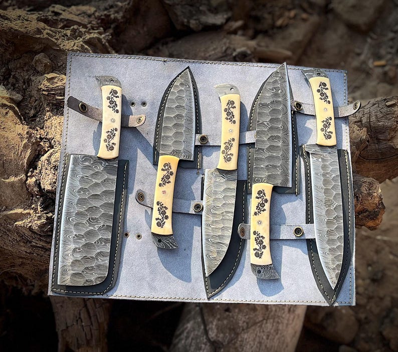 Handmade 5 piece chef knife set featuring natural white handles crafted from natural material with high carbon steel blades arranged inside a premium hand stitched leather roll kit. The image shows the complete kitchen knife collection designed for professional chefs and home cooks who love quality tools. This artisan knife set is perfect for anniversary gifts, wedding gifts, housewarming presents and culinary collectors looking for beautiful handmade kitchen knives with safe