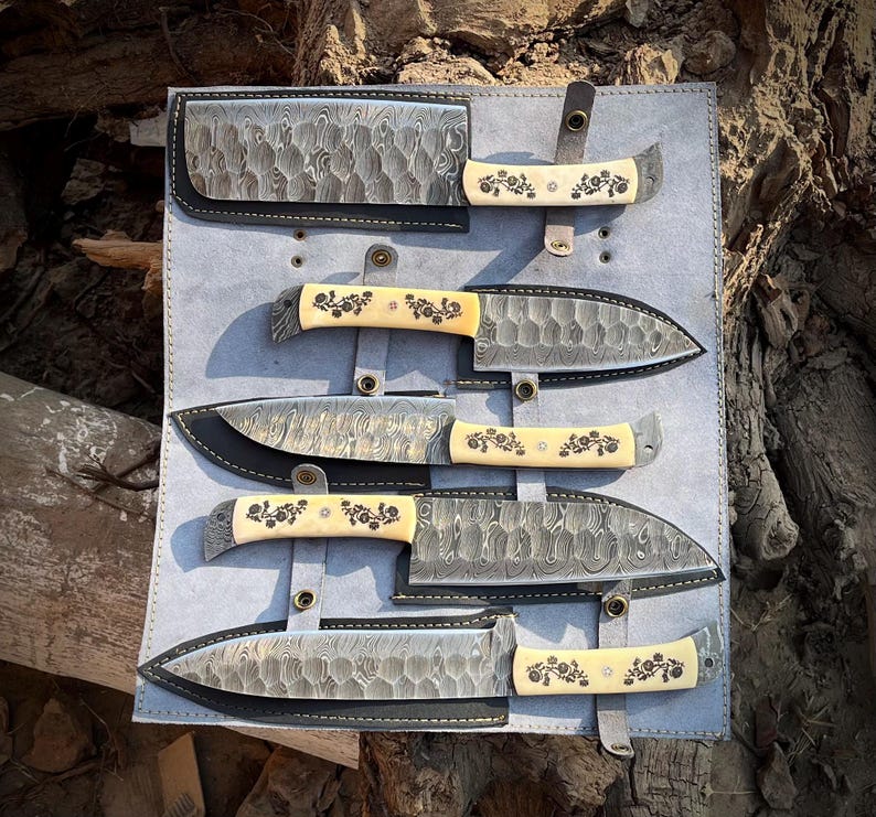 Complete view of the natural white handle 5 pcs chef knife set with leather roll kit laid out for display. Shows carbon steel blades, natural material handles and artisan workmanship. This handcrafted kitchen knife collection is designed for daily cooking, professional chefs and home kitchens.