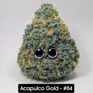 May include: A plush, green and gold-colored creature with large, pink-rimmed eyes. The text "Acapulco Gold - #84" is displayed in a black rectangle at the bottom of the image. The creature has a textured, fuzzy appearance.