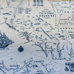 May include: A detailed map of the Thirteen Colonies from 1776, rendered in blue ink on a cream-colored background. The map includes illustrations of a sailing ship, a compass rose, and a cannon. The text "1776 MAP OF THE THIRTEEN COLONIES" is prominently displayed.
