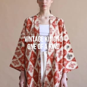 Peut inclure: Un kimono vintage avec un motif répétitif de losanges orange rouille et crème, agrémenté de petites fleurs sombres à l'intérieur. Le texte VINTAGE KIMONO ONE OF A KIND est imprimé en blanc au centre du vêtement.