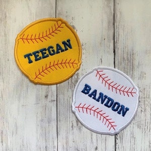 Può includere: Due toppe ricamate a tema baseball con cuciture rosse. Una toppa è gialla con il nome "Teegan" in lettere blu. L'altra toppa è bianca con il nome "Bandon" in lettere blu.