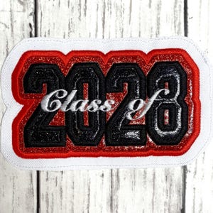 May include: A rectangular embroidered patch featuring the black glittery numbers 2028 with a red glittery border and a white stitched edge. The word Class of is embroidered in white cursive script across the center of the black numbers.