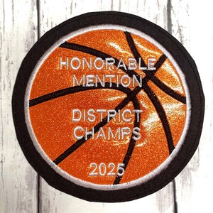 May include: Orange and black basketball patch with white text that reads "Honorable Mention District Champs 2025".