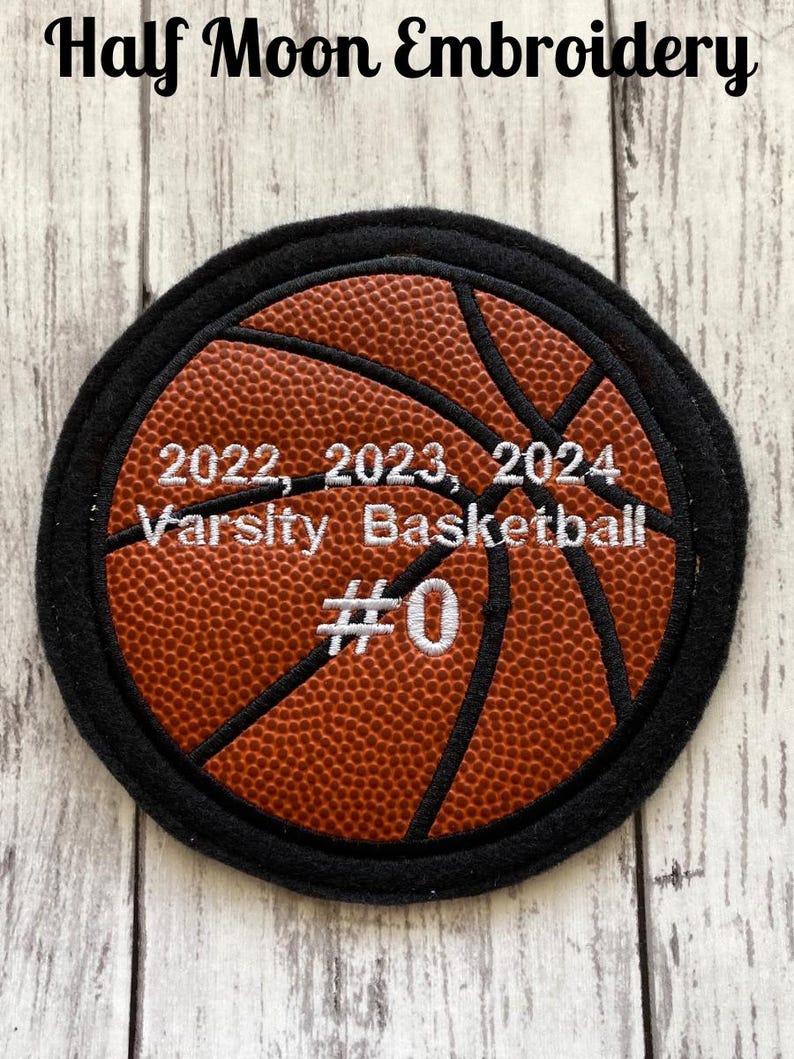 May include: A black and orange embroidered basketball patch with the text "2022, 2023, 2024 Varsity Basketball #0".