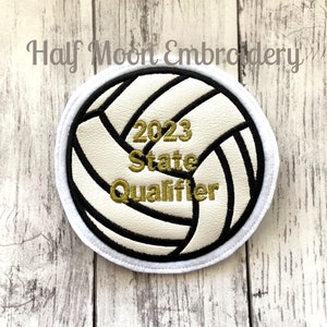 May include: White volleyball with black stitching and gold embroidery that reads "2023 State Qualifier".
