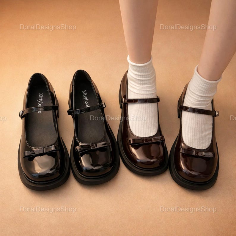 May include: Black and brown patent leather Mary Jane shoes with a bow detail and a strap closure. The shoes have a chunky sole and are displayed with white socks. The brand name "Kittyboot" is visible on the insole.