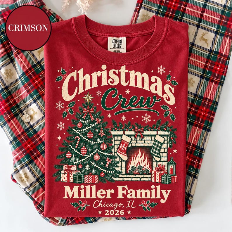 May include: A crimson t-shirt featuring a graphic of a decorated Christmas tree, a fireplace with stockings, and the text "Christmas Crew", "Miller Family", "Chicago, IL", and "2026". The shirt has a Comfort Colors label at the inner neckline.