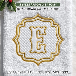 Op de afbeelding: Een witte badstof handdoek met een geborduurde gouden en witte letter E in een decoratief kader. De tekst luidt: 3 MATEN | VAN 7,1 CM TOT 12,7 CM, DIRECTE DOWNLOAD | 10,2 CM X 10,2 CM RING, en bestandsformaten .DST | .EXP | .HUS | .JEF | .PES | .VP3 | .XXX.