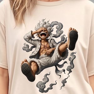 May include: Cream-colored t-shirt featuring a vibrant illustration of a character from the anime series One Piece. The character is depicted mid-air, laughing with arms and legs outstretched, and surrounded by swirling smoke. The character is wearing a white outfit.