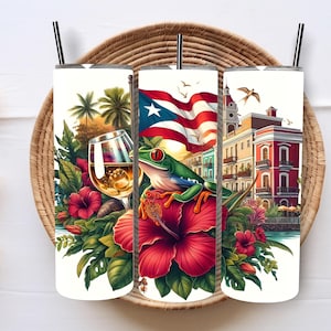 May include: Three white insulated tumblers with black straws, each featuring a different Puerto Rican-themed design. One shows a wine glass, another a frog and the Puerto Rican flag, and the third a building. All are surrounded by tropical flowers.