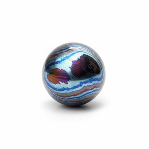 Pu&ograve; includere: Un oggetto sferico con un sorprendente motivo a spirale di blu, viola e arancione. L'orbita sembra metallica e ha una superficie lucida. Il design ricorda una galassia in miniatura o una gemma. La sfera misura circa 3 cm di diametro.