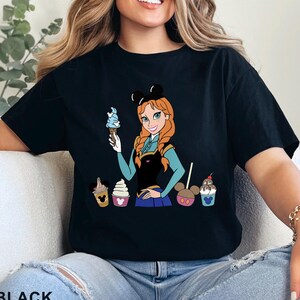 May include: A white ceramic mug with a black handle and the text "But First, Coffee" in a black, handwritten-style font. The mug is on a white surface.