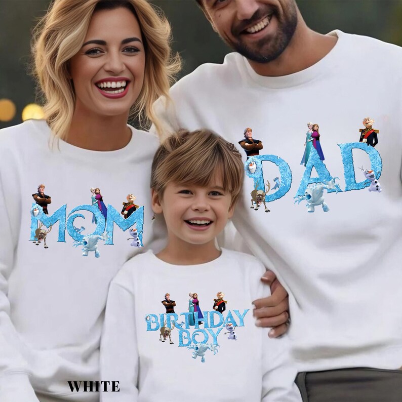 Op de afbeelding: Witte sweatshirts met de woorden "MOM", "DAD" en "BIRTHDAY BOY" in blauw, met personages uit een populaire animatiefilm. De sweatshirts worden gedragen door een gezin van drie, lachend in de camera.