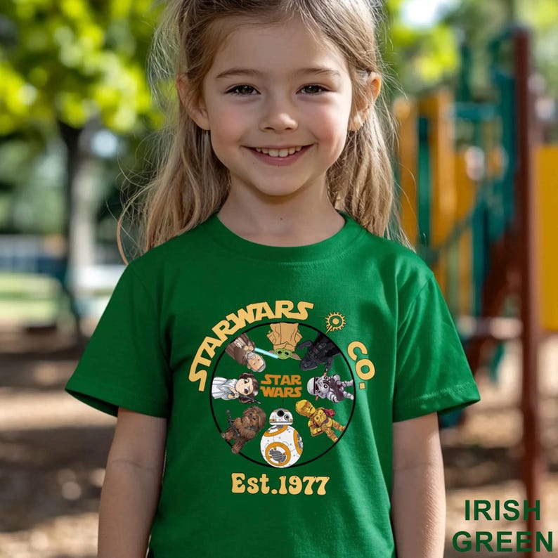 Peut inclure: Un t-shirt vert avec un motif Star Wars, comprenant des personnages et le texte "Est.1977". Le t-shirt est de couleur vert irlandais vif.