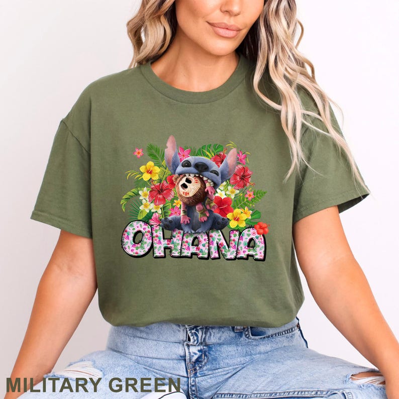 May include: Military green t-shirt featuring a colorful graphic of Stitch wearing a floral lei and a Stitch hat, surrounded by flowers. The word "Ohana" is printed in a floral font.