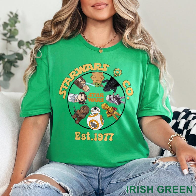 Peut inclure: T-shirt vert irlandais avec un motif circulaire repr&eacute;sentant des personnages de Star Wars et le texte "STARWARS CO. Est.1977". Le t-shirt a un col rond et des manches courtes. Le texte "IRISH GREEN" est imprim&eacute; en bas.