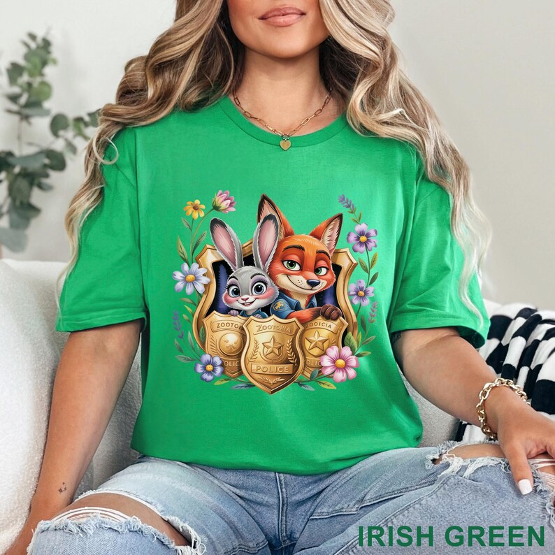Puede incluir: Camiseta verde irland&eacute;s con un dise&ntilde;o de Judy Hopps y Nick Wilde de Zootopia, enmarcado por flores y placas de polic&iacute;a. La camiseta tiene mangas cortas y cuello redondo. El texto "IRISH GREEN" est&aacute; en la parte inferior.