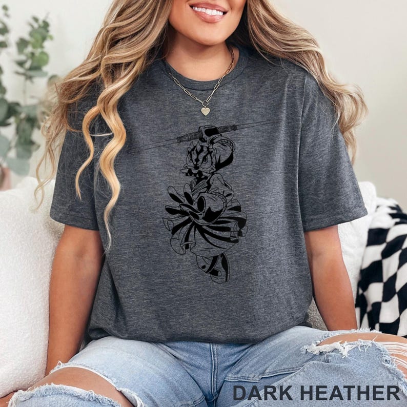 Op de afbeelding: Donkergrijs t-shirt met een zwart grafisch ontwerp. De afbeelding is een gestileerde illustratie van een personage. De tekst "DARK HEATHER" staat onderaan de afbeelding.