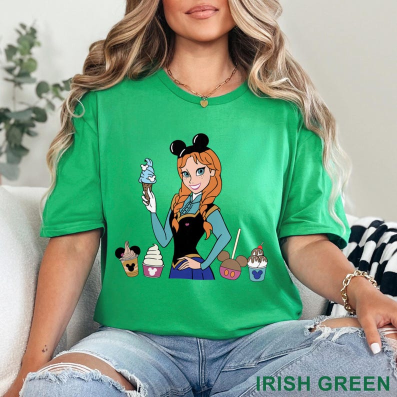 May include: Irish green t-shirt featuring a cartoon illustration of a character holding blue ice cream, with several ice cream treats below. The shirt has the text "IRISH GREEN" at the bottom. The character is wearing a black top and blue skirt.