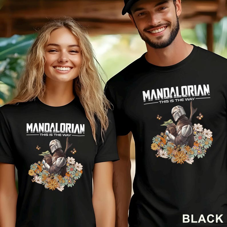 May include: Black t-shirts featuring a graphic of The Mandalorian and Grogu surrounded by flowers. The text "MANDALORIAN - THIS IS THE WAY" is printed above the image. The word "BLACK" is printed at the bottom of the image.