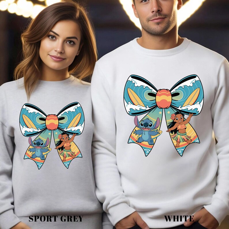 Puede incluir: Sudaderas deportivas grises y blancas con un gran dise&ntilde;o de lazo con los personajes de dibujos animados Stitch y Lilo. El lazo tiene olas azules, tablas de surf amarillas y un centro naranja. El texto "SPORT GREY" y "WHITE" est&aacute; en la parte inferior.