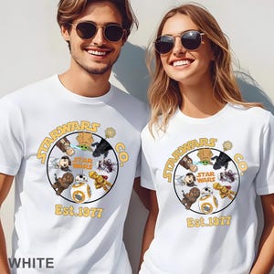 Peut inclure: T-shirts blancs avec un motif circulaire repr&eacute;sentant des personnages de Star Wars et le texte "STARWARS CO." et "Est. 1977" en jaune. Le motif comprend des personnages comme BB-8 et Yoda.