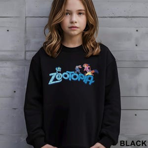 May include: Black sweatshirt featuring the word "Zootopia" in blue and a colorful graphic of characters from the movie. The word "BLACK" is printed in white at the bottom right corner.