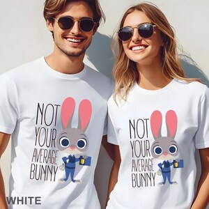 Puede incluir: Camisetas blancas con el texto "NOT YOUR AVERAGE BUNNY" y un personaje de conejo de dibujos animados. El conejo tiene pelo gris, orejas rosas y lleva un uniforme azul. La palabra "WHITE" est&aacute; abajo.