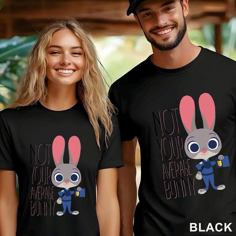 Puede incluir: Camisetas negras con un dise&ntilde;o de conejo de dibujos animados y el texto "NOT YOUR AVERAGE BUNNY". El conejo tiene orejas rosas, un uniforme azul y un malet&iacute;n. La palabra "BLACK" est&aacute; en la parte inferior.