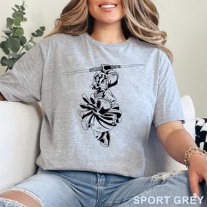 Op de afbeelding: Sportgrijs t-shirt met een zwart-wit afbeelding van een personage met een lichtzwaard. De afbeelding is een gestileerde illustratie. Het shirt is gemaakt van een zacht materiaal en heeft korte mouwen. De tekst "SPORT GREY" staat onderaan.