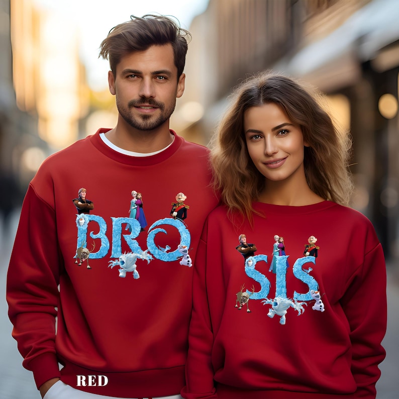 Op de afbeelding: Rode sweatshirts met de woorden "BRO" en "SIS" in blauw, met figuren uit een animatiefilm. Een bijpassende set, ideaal voor broers en zussen of koppels. Het woord "RED" staat onderaan.
