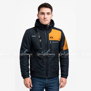Puede incluir: Una chaqueta con capucha de color azul marino oscuro que presenta un panel amarillo mostaza en la parte superior del pecho izquierdo y la manga. Incluye una cremallera central, varios bolsillos diagonales y texto blanco en el pecho.