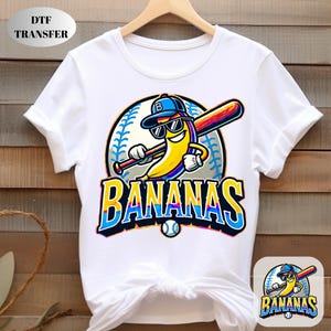May include: White t-shirt with a cartoon banana wearing sunglasses and a baseball cap, holding a baseball bat. The word "BANANAS" is written in a colourful, stylised font. A small baseball is below the text. The shirt has a DTF TRANSFER label.