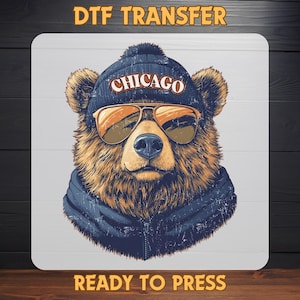 May include: DTF transfer design featuring a bear wearing a navy blue beanie with "CHICAGO" in white, and sunglasses. The bear is wearing a navy blue jacket. The words "READY TO PRESS" are at the bottom.