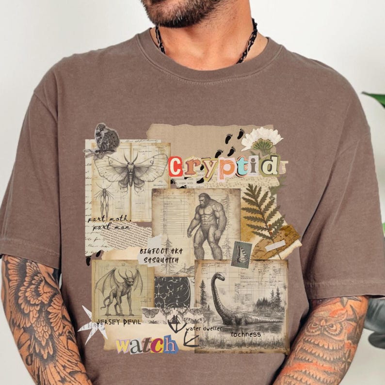A man wears a Comfort Colors Espresso t shirt with a Cryptozoology design featuring Mothman, Bigfoot, Lochness and the Jersey Devil in a vintage field journal style. Intended for camping, hiking and outdoorsy activities or for lovers of spooky folklore.