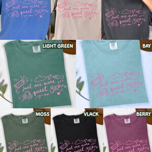 May include: A selection of t-shirts in shades such as blue, cream, and green. Each shirt displays the pink phrase "Just one more quest" alongside gaming-themed illustrations, including a games console and headphones. The shirts are made of a soft fabric.