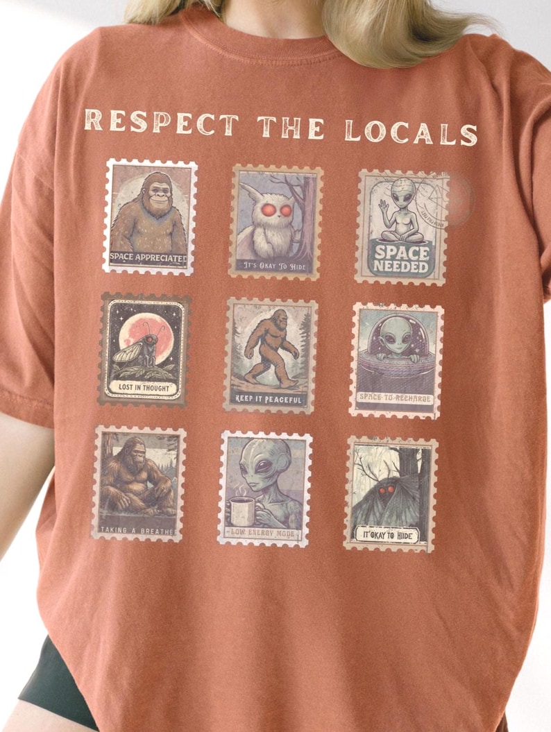 Yam colored Comfort Colors t-shirt with "Respect The Locals" cryptid stamp graphic, featuring Bigfoot, Mothman, and Alien stamps. Ideal for cryptid lovers and introverts.