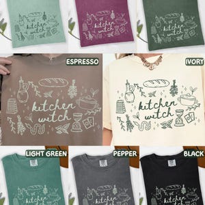 Kitchen Witch Comfort Colors shirt shown in Bay, Berry, Moss, Espresso, Ivory, Light Green, Pepper, and Black color options featuring hand-drawn cottagecore kitchen and witchy illustrations surrounding the phrase "kitchen witch."