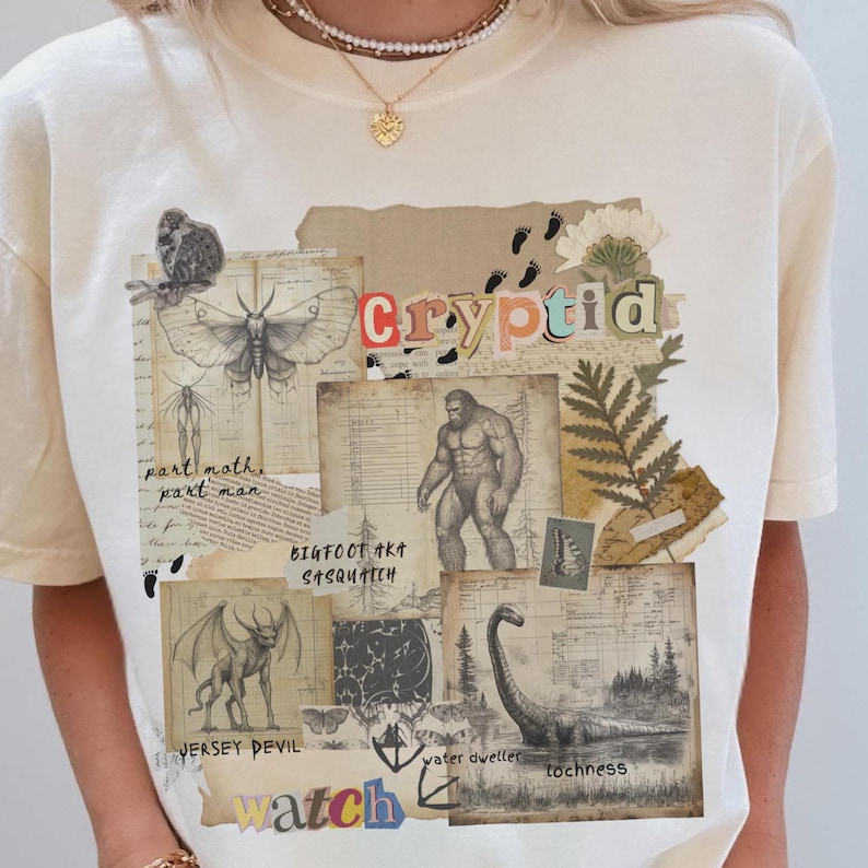 A Woman wears a Comfort Colors Ivory t shirt with a Cryptozoology design featuring Mothman, Bigfoot, Lochness and the Jersey Devil in a vintage field journal style. Intended for camping, hiking and outdoorsy activities or for lovers of spooky folklore.