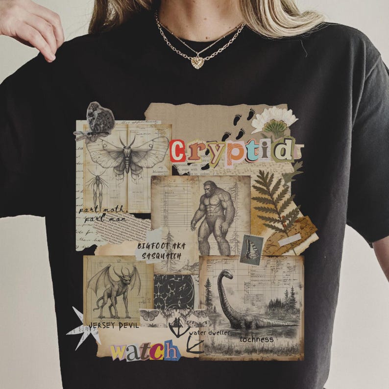 A Woman wears a Comfort Colors Black t shirt with a Cryptozoology design featuring Mothman, Bigfoot, Lochness and the Jersey Devil in a vintage field journal style. Intended for camping, hiking and outdoorsy activities or for lovers of spooky folklore.
