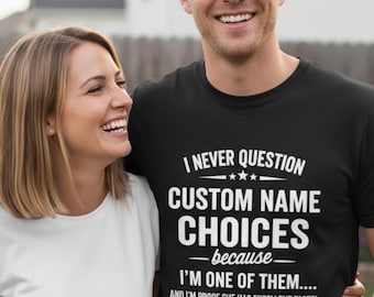 May include: A black t-shirt with white text that reads "I NEVER QUESTION CUSTOM NAME CHOICES - because - I'M ONE OF THEM.... AND I'M PROOF SHE HAS EXCELLENT TASTE!". A woman in a white shirt and a man are smiling.