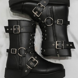 Handmade black leather wrestling boots designed for pro wrestlers and performers. These durable wrestling shoes feature lace-up closure, side zipper, and multiple buckle straps for a secure fit and bold style. Perfect for wrestling matches, cosplay, costumes, and stage performances. Crafted from premium quality leather for long-lasting wear, comfort, and stability in the ring. Unisex wrestling boots available in custom sizes for men and women.