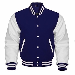 Op de afbeelding: Een marineblauwe en witte varsity-jas met witte mouwen, een marineblauwe body en wit gestreepte manchetten en kraag. De jas heeft witte knopen en twee voorzakken.