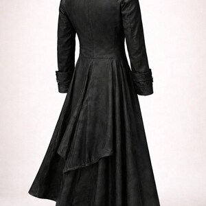 May include: A long, black coat with a flared skirt and a tailored fit. The coat features a notched collar, long sleeves with buttoned cuffs, and a back vent. The fabric appears to be a matte material, giving the coat a sleek, gothic aesthetic.