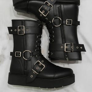 Pair of leather wrestling boots shown side by side, highlighting the bold buckle straps and strong leather build. Designed for professional wrestling matches and cosplay costumes, these unisex boots feature premium leather, durable soles, and lace-up closure for a snug fit. Ideal for stage performance and cosplay characters requiring wrestling gear. Handmade craftsmanship guarantees long-lasting wear and unique style for both men’s and women’s wrestling footwear collections.